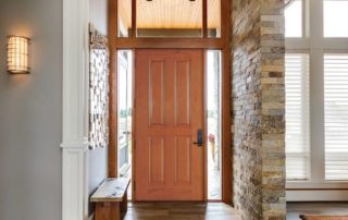 Wood front door with glass sidelights and transom windows in a bright entryway