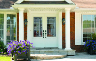 Double entry doors with Lexington decorative glass inserts on a brick home with white columns